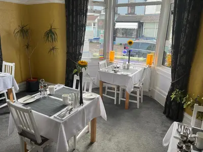 a restaurant with white tables and chairs and a window at Glen Guest House in Blackpool
