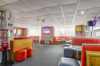 a restaurant with red chairs and tables and a tv at The Sandringham Court Hotel & Apartment Welcoming Large and Small Groups for 16 years in Blackpool