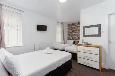 a bedroom with two beds and a mirror at The Sandringham Court Hotel & Apartment Welcoming Large and Small Groups for 16 years in Blackpool