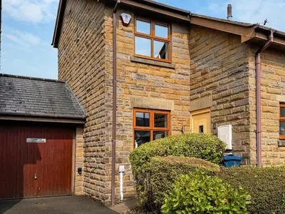 a brick house with a door and a garage at Church View in Longridge