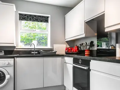 a kitchen with white cabinets and a window at Church View in Longridge