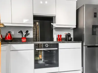 a kitchen with white cabinets and a black oven at Church View in Longridge