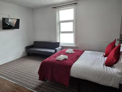 a bedroom with a bed with a red blanket and a couch at Wilsons Lodge in Blackpool