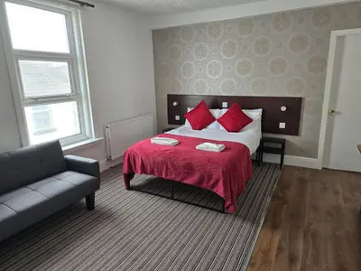 a bedroom with a bed with red pillows and a couch at Wilsons Lodge in Blackpool
