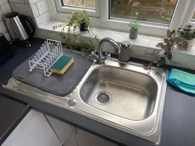 a kitchen sink with a dish drying rack on it at Stylish Home - Close to City Centre, Anfield Stadium - Free Parking in Litherland