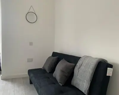 a black couch in a room with a white wall at Stylish Home - Close to City Centre, Anfield Stadium - Free Parking in Litherland