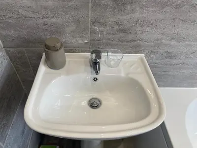 a white sink with a glass on top of it at Stylish Home - Close to City Centre, Anfield Stadium - Free Parking in Litherland