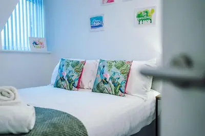 a white bed with colorful pillows on top of it at Rocky Lane Urban Apartments by Charming Apartments - Flat 5 in Liverpool