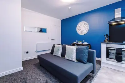 a living room with a couch and a blue wall at Rocky Lane Urban Apartments by Charming Apartments - Flat 5 in Liverpool