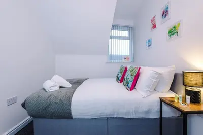 a bedroom with a bed with white sheets and colorful pillows at Rocky Lane Urban Apartments by Charming Apartments - Flat 5 in Liverpool