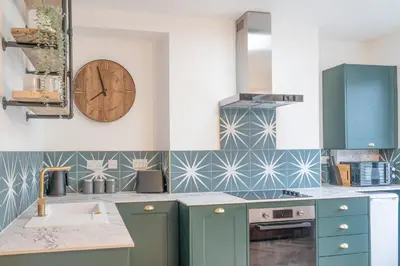 a kitchen with blue cabinets and a clock on the wall at Beautifully Designed 1 Bed Flat in Morecambe