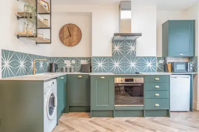 a kitchen with blue cabinets and a washer and dryer at Beautifully Designed 1 Bed Flat in Morecambe