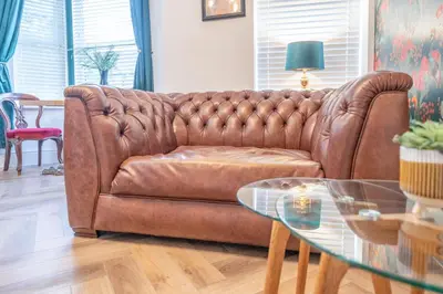 a brown leather couch in a living room with a glass table at Beautifully Designed 1 Bed Flat in Morecambe