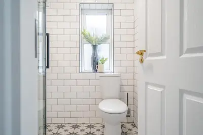 a white bathroom with a toilet and a window at Gorgeous New 1 Bedroom Penthouse Flat in Morecambe