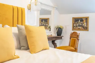 a bedroom with a bed with yellow pillows and a chair at Gorgeous New 1 Bedroom Penthouse Flat in Morecambe
