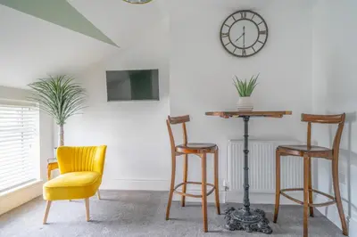 a room with chairs and a table and a clock at Gorgeous New 1 Bedroom Penthouse Flat in Morecambe