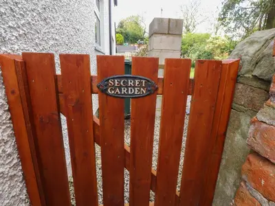 a wooden fence with a sign that reads secret garden at Stork Cottage in Lancaster
