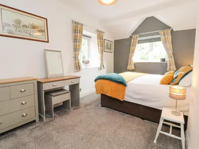 a bedroom with a bed and a desk and a window at Stork Cottage in Lancaster