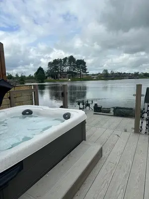 a hot tub sitting on a dock next to a body of water at Luxurious and Peaceful Lakeside House, Clitheroe in Clitheroe