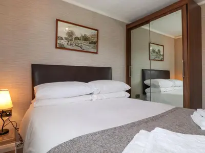 a bedroom with a large white bed and a mirror at Capenwray in Carnforth
