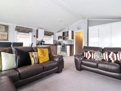a living room with two leather couches and a kitchen at Capenwray in Carnforth