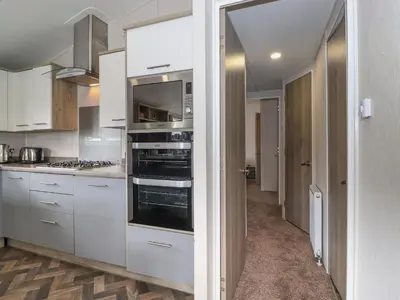 a kitchen with white cabinets and stainless steel appliances at Coniston in Carnforth