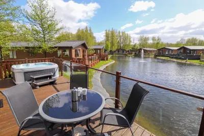 a deck with a table and chairs next to a body of water at Coniston in Carnforth
