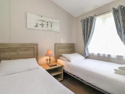 two beds in a room with a window at Coniston in Carnforth