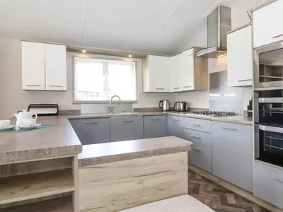 a kitchen with white cabinets and stainless steel appliances at Coniston in Carnforth