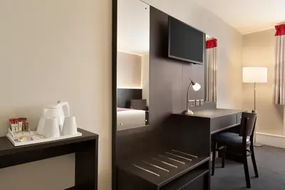 a hotel room with a desk and a mirror at Ramada Chorley South in Chorley