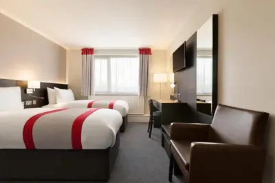 a hotel room with two beds and a chair at Ramada Chorley South in Chorley