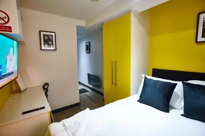 a hotel room with a bed and a flat screen tv at MCCARTNEY SUITE 5 Bedrooms, 5 bathrooms in Liverpool