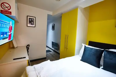 a hotel room with a bed and a flat screen tv at MCCARTNEY SUITE 5 Bedrooms, 5 bathrooms in Liverpool