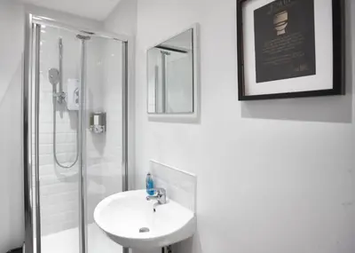 a white bathroom with a sink and a shower at MCCARTNEY SUITE 5 Bedrooms, 5 bathrooms in Liverpool