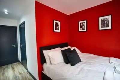 a bedroom with a red wall with a bed at MCCARTNEY SUITE 5 Bedrooms, 5 bathrooms in Liverpool