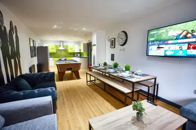 a living room with a couch and a tv at MCCARTNEY SUITE 5 Bedrooms, 5 bathrooms in Liverpool