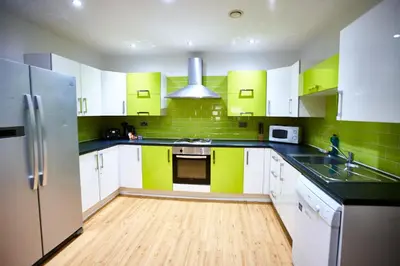 a kitchen with green and white cabinets and a refrigerator at MCCARTNEY SUITE 5 Bedrooms, 5 bathrooms in Liverpool