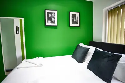 a green bedroom with a white bed and a green wall at STARR SUITE 6 Bedrooms, 6 Bathrooms in Liverpool