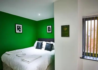 a bedroom with green walls and a bed with white sheets at STARR SUITE 6 Bedrooms, 6 Bathrooms in Liverpool