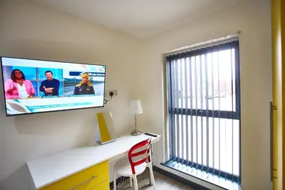 a room with a tv on a wall with a desk at STARR SUITE 6 Bedrooms, 6 Bathrooms in Liverpool