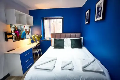 a blue bedroom with a bed and a desk at STARR SUITE 6 Bedrooms, 6 Bathrooms in Liverpool