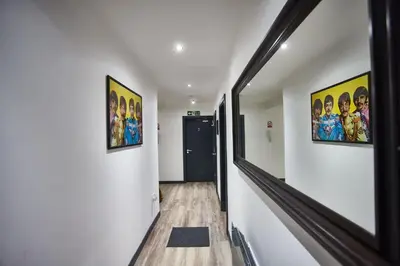 a hallway with two paintings on the walls and a hallway with a door at LENNON SUITE 4 Bedrooms, 4 Bathrooms in Liverpool