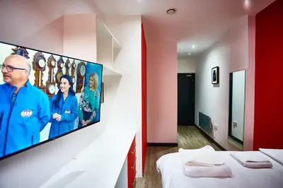 a room with two beds and a tv on the wall at LENNON SUITE 4 Bedrooms, 4 Bathrooms in Liverpool