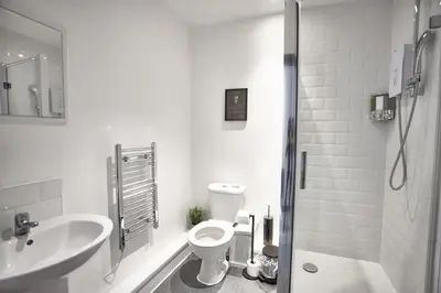 a white bathroom with a toilet and a sink at LENNON SUITE 4 Bedrooms, 4 Bathrooms in Liverpool