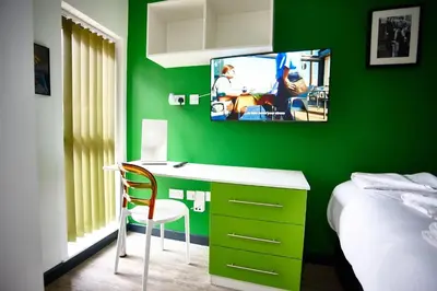 a green bedroom with a desk and a tv on a green wall at LENNON SUITE 4 Bedrooms, 4 Bathrooms in Liverpool