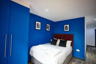 a bedroom with blue walls and a bed with white sheets at LENNON SUITE 4 Bedrooms, 4 Bathrooms in Liverpool
