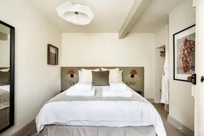 a bedroom with a large bed with white sheets at Drakes Cottage in Cartmel