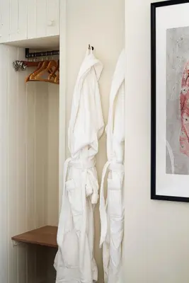 a room with white clothes hanging on a wall at Drakes Cottage in Cartmel