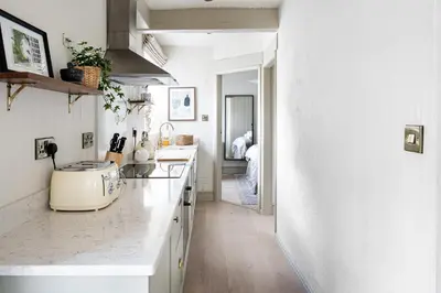 a kitchen with white cabinets and a counter top at Drakes Cottage in Cartmel