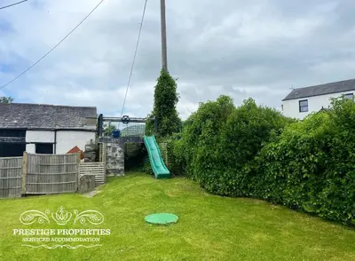 a yard with a green slide in the grass at Millstream Barn by Prestige Properties SA in Millom